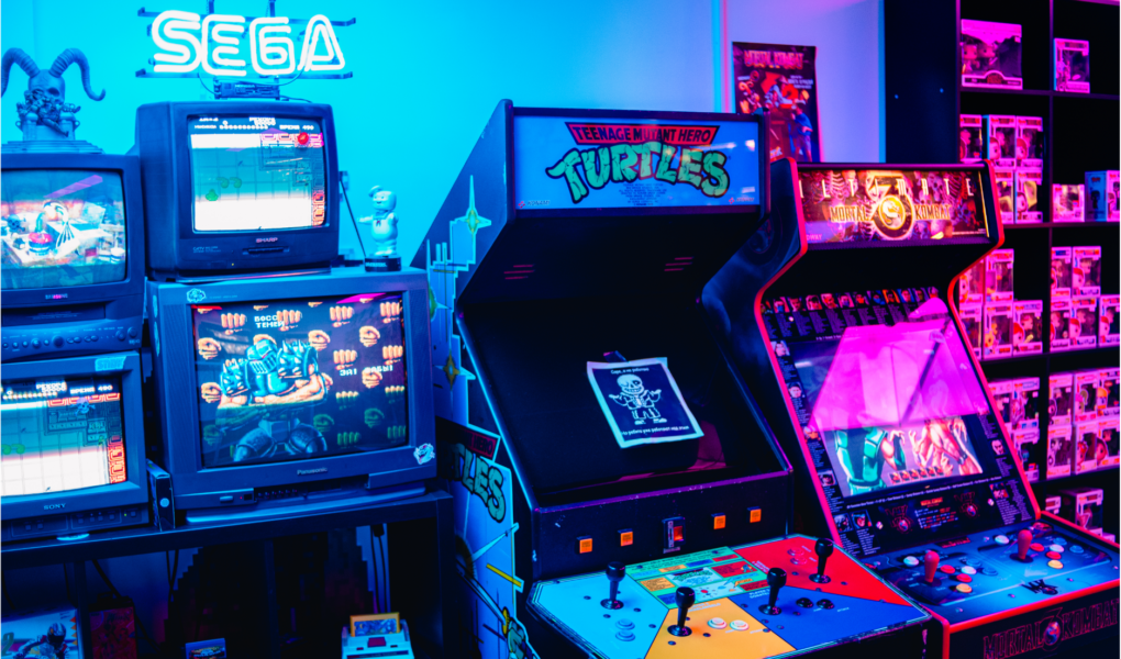 Des bornes d'arcade avec des jeux en tout genre et un fond coloré bleu et rose