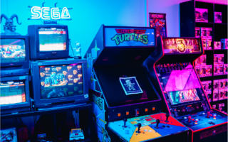 Des bornes d'arcade avec des jeux en tout genre et un fond coloré bleu et rose